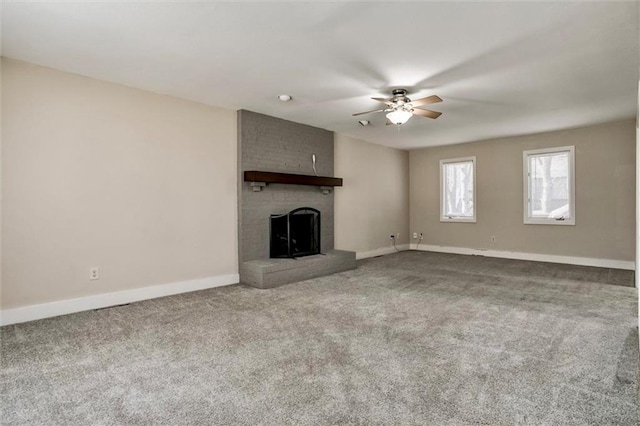 unfurnished living room with ceiling fan, carpet floors, a fireplace, and baseboards