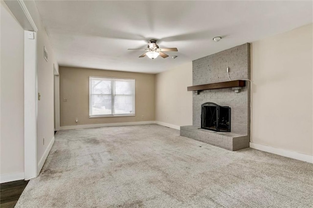 unfurnished living room featuring dark colored carpet, a brick fireplace, a ceiling fan, and baseboards