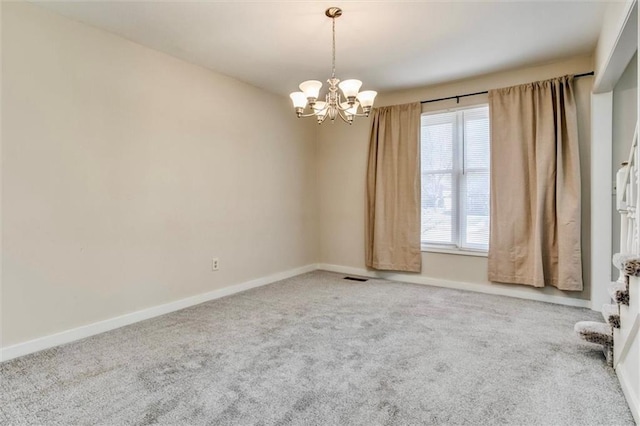 carpeted spare room featuring a notable chandelier, visible vents, and baseboards