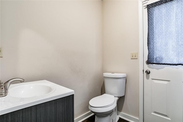 half bath with vanity, toilet, and baseboards