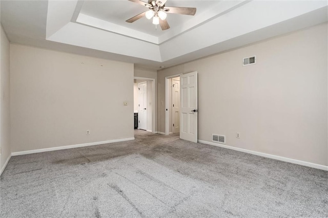 empty room featuring baseboards, visible vents, a raised ceiling, and a ceiling fan