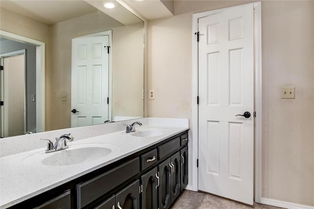 bathroom with double vanity, a sink, and baseboards