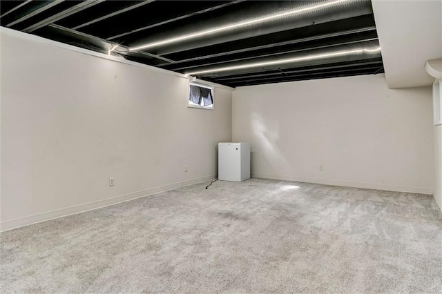 below grade area featuring light carpet and baseboards