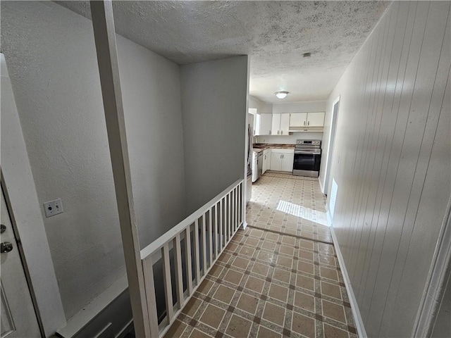 hallway with a textured ceiling and wood walls