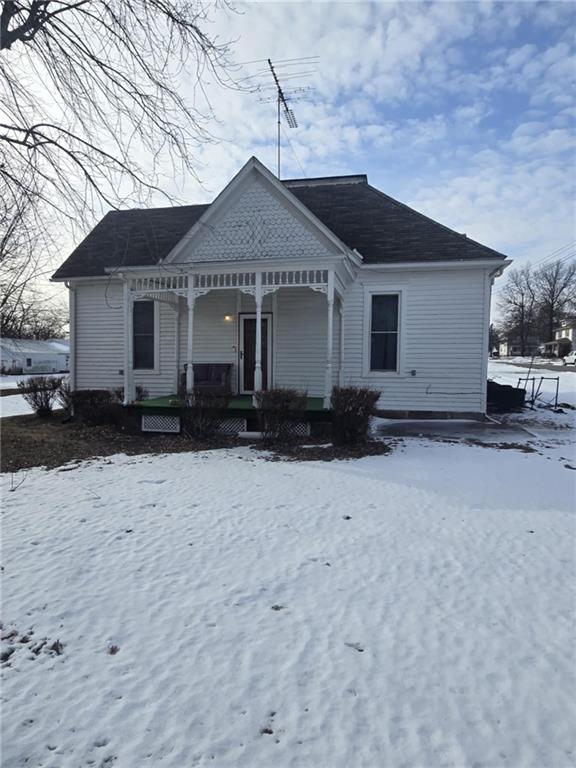 snow covered rear of property with covered porch