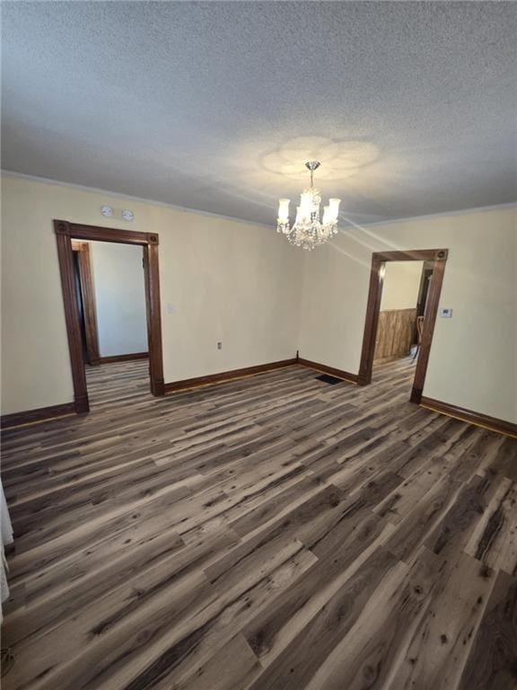 spare room featuring dark wood-type flooring, an inviting chandelier, and a textured ceiling