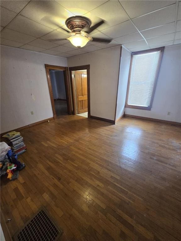 empty room with ceiling fan, a paneled ceiling, and hardwood / wood-style flooring