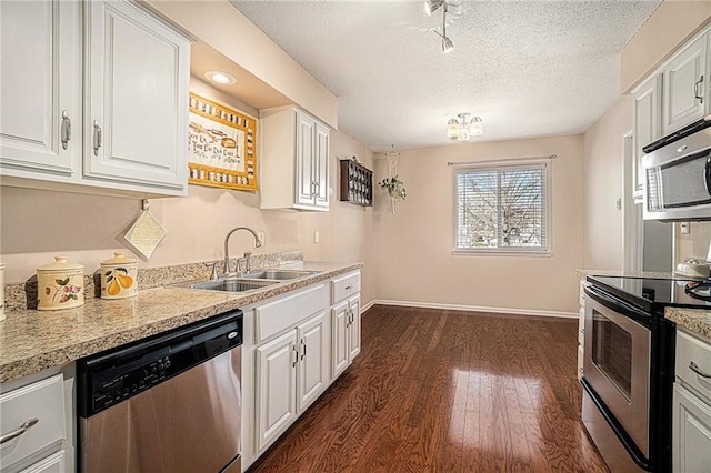 kitchen with appliances with stainless steel finishes, sink, white cabinets, and dark hardwood / wood-style flooring