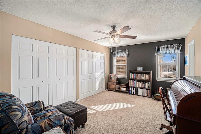 carpeted office space with a textured ceiling and ceiling fan