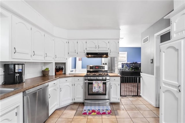 kitchen featuring appliances with stainless steel finishes, light tile patterned flooring, and white cabinetry