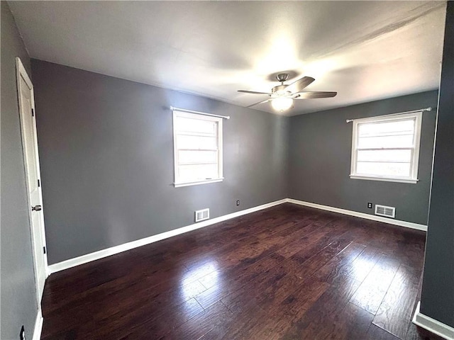 empty room featuring ceiling fan, dark hardwood / wood-style flooring, and a wealth of natural light