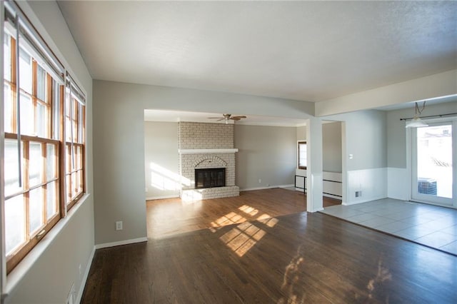 unfurnished living room featuring ceiling fan, a fireplace, and wood-type flooring