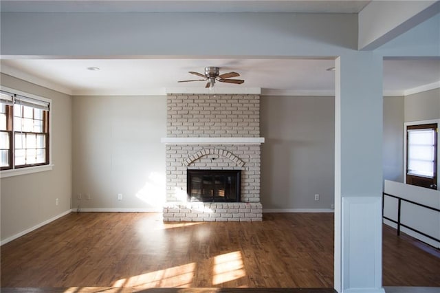 unfurnished living room featuring ceiling fan, a brick fireplace, dark hardwood / wood-style flooring, and crown molding