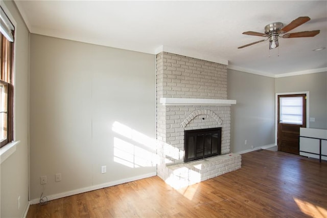 unfurnished living room with hardwood / wood-style flooring, a brick fireplace, and plenty of natural light