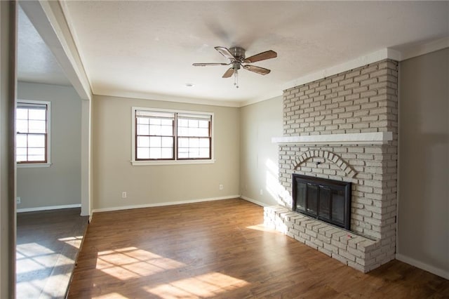 unfurnished living room with ceiling fan, hardwood / wood-style floors, ornamental molding, and a fireplace