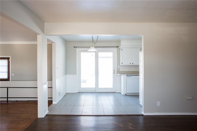 interior space featuring pendant lighting, white cabinets, dishwasher, decorative backsplash, and light hardwood / wood-style flooring