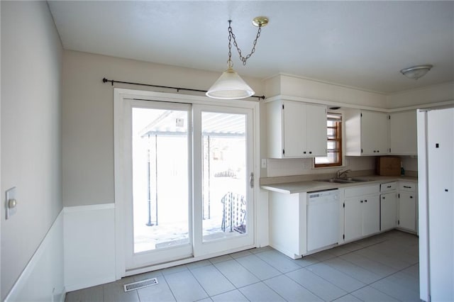 kitchen with white cabinets, dishwasher, light tile patterned floors, and pendant lighting