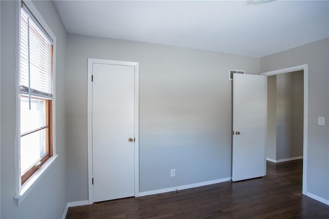 unfurnished bedroom with dark wood-type flooring and multiple windows