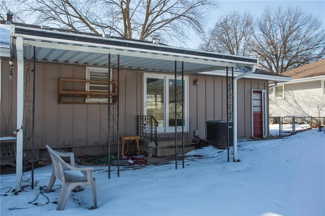 snow covered property entrance with central AC