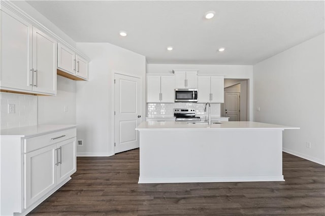 kitchen featuring white cabinetry, stainless steel appliances, and an island with sink