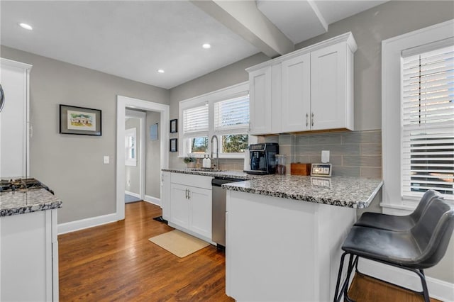 kitchen featuring sink, a breakfast bar area, appliances with stainless steel finishes, light stone counters, and white cabinets