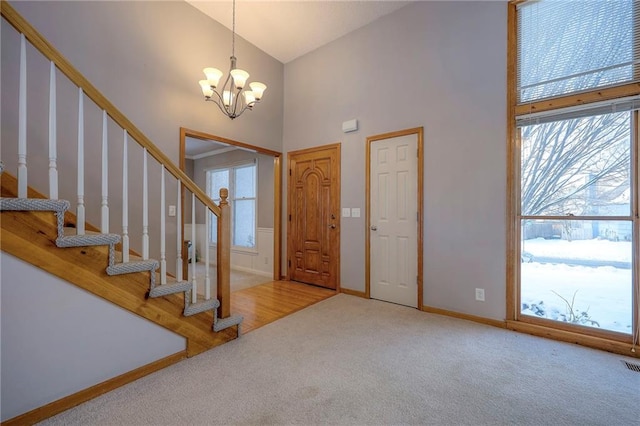 carpeted entryway featuring high vaulted ceiling and an inviting chandelier