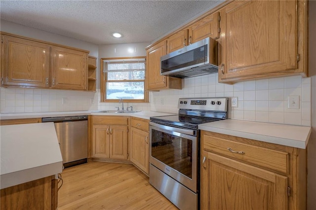 kitchen featuring light hardwood / wood-style floors, appliances with stainless steel finishes, a textured ceiling, tasteful backsplash, and sink