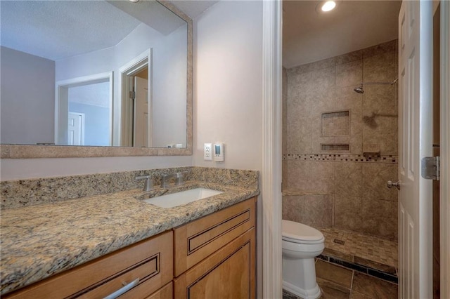 bathroom featuring vanity, toilet, and tiled shower