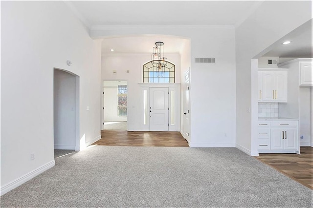 carpeted foyer entrance with a high ceiling and ornamental molding