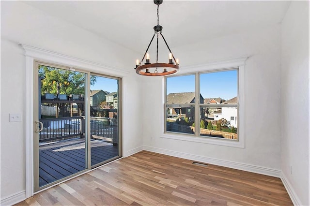 unfurnished dining area featuring an inviting chandelier and hardwood / wood-style floors