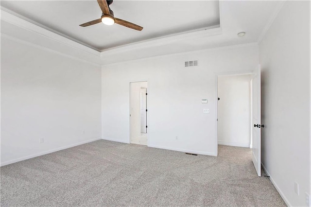 unfurnished room with ornamental molding, light colored carpet, a raised ceiling, and ceiling fan