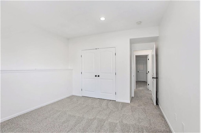 unfurnished bedroom with light carpet and a closet