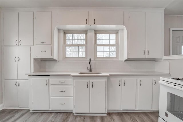 kitchen featuring sink, white electric range oven, white cabinetry, and tasteful backsplash