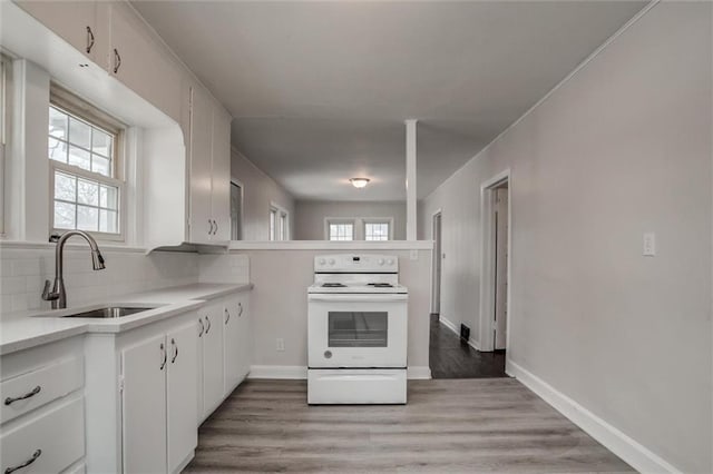 kitchen featuring sink, white range with electric stovetop, white cabinets, and light wood-type flooring