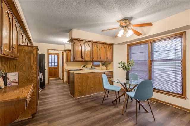 kitchen with a textured ceiling, dark hardwood / wood-style floors, ceiling fan, and black fridge