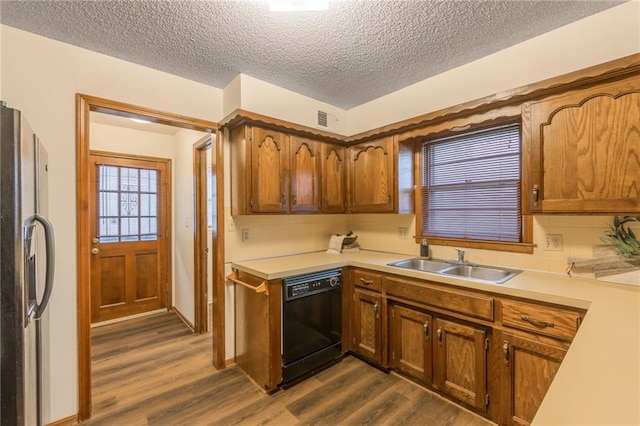 kitchen featuring sink, dark wood-type flooring, stainless steel refrigerator, dishwasher, and a textured ceiling