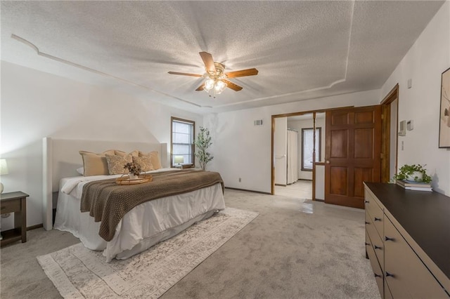 bedroom with ceiling fan, light colored carpet, and a textured ceiling