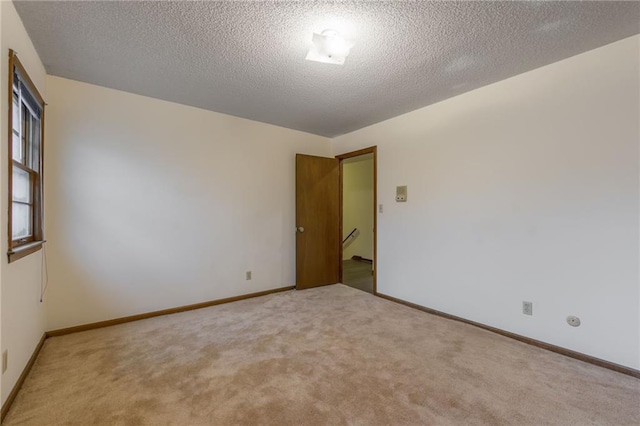 empty room featuring light carpet and a textured ceiling