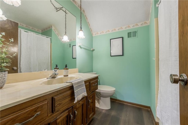 bathroom with vanity, hardwood / wood-style floors, vaulted ceiling, and toilet