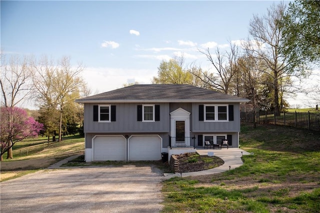 raised ranch featuring fence, a garage, and aphalt driveway