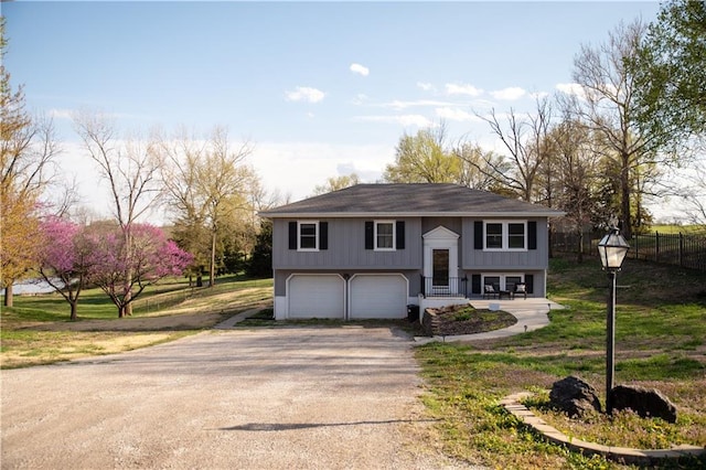 split foyer home with dirt driveway, an attached garage, and fence