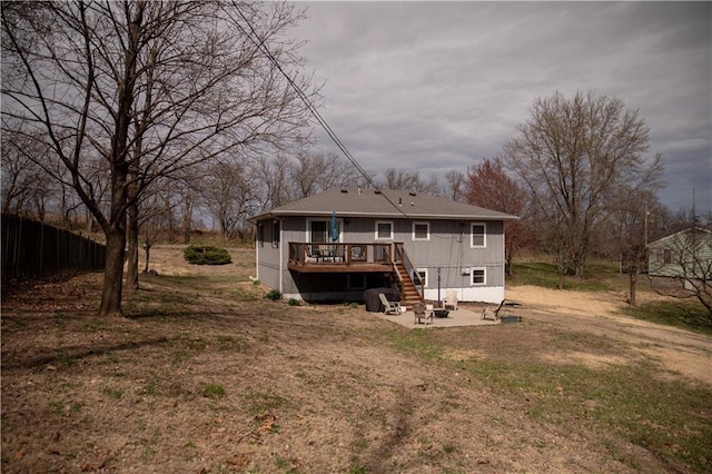 rear view of house with a deck, a fire pit, a patio area, fence, and stairway