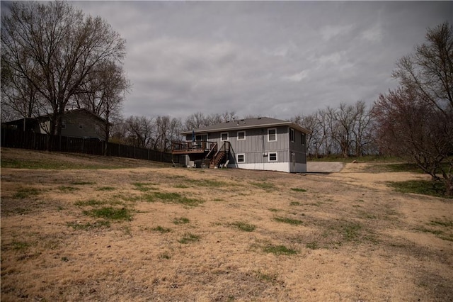 back of property with fence, a deck, and stairway