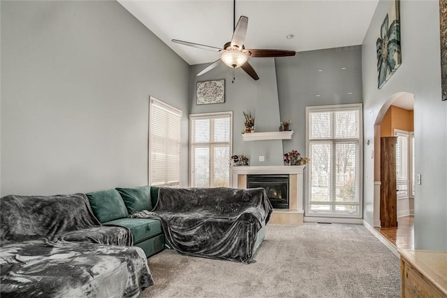 living room featuring high vaulted ceiling, plenty of natural light, a tile fireplace, and carpet flooring