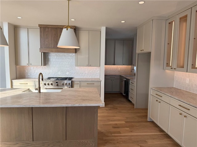 kitchen featuring hanging light fixtures, stainless steel stove, light wood-type flooring, black dishwasher, and decorative backsplash