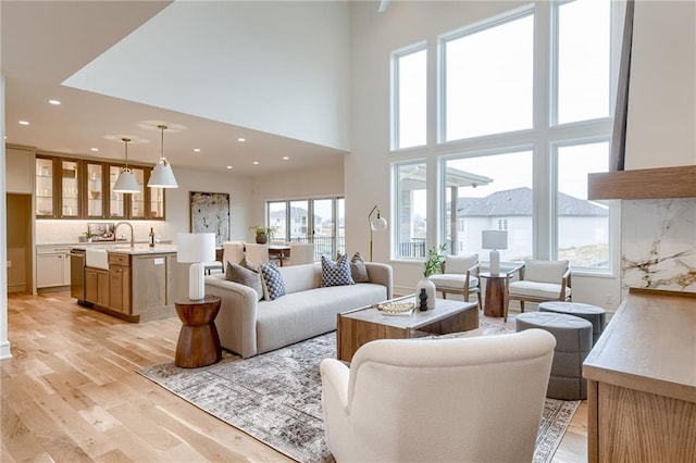 living room with sink, a towering ceiling, and light hardwood / wood-style flooring