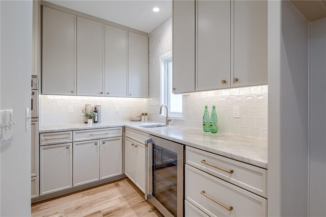 kitchen with wine cooler, sink, tasteful backsplash, and light stone countertops