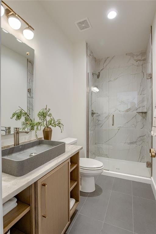 bathroom with vanity, toilet, tile patterned flooring, and a shower with door