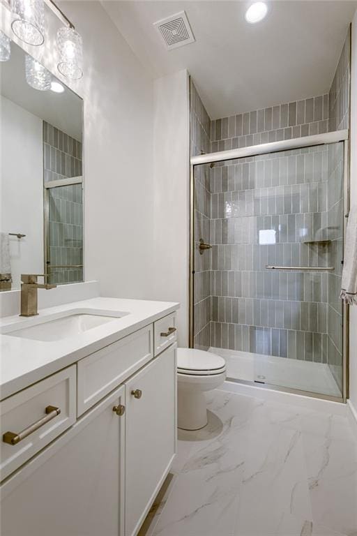 bathroom featuring vanity, a shower with shower door, and toilet