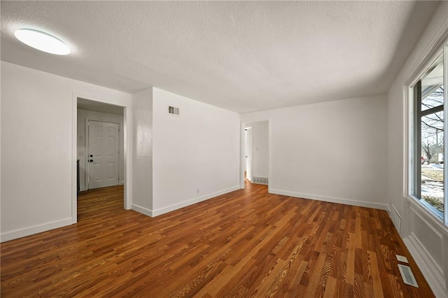 spare room with dark hardwood / wood-style floors and a textured ceiling